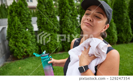 Woman in cap resting and wiping sweat with towel Woman in cap resting and wiping sweat with towel 129247354