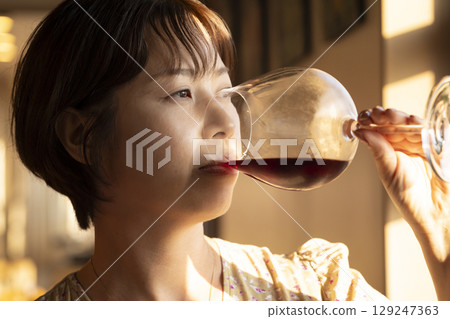 A woman drinking wine 129247363