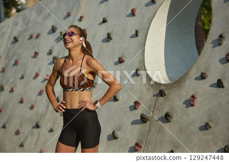 Woman relishing open-air exercise during sunny day climbing wall Woman relishing open-air exercise during sunny day climbing wall 129247448