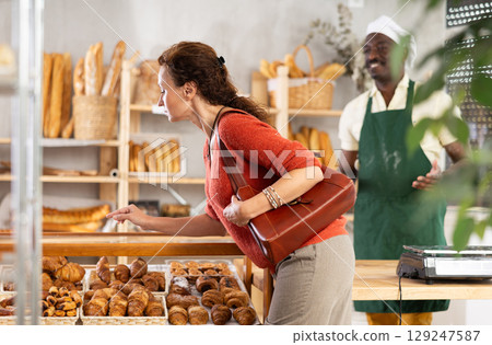 Female customer choosing fresh pastry in bakehouse Female customer choosing fresh pastry in bakehouse 129247587