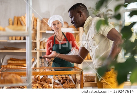 Man customer choosing fresh pastry in bakehouse 129247614