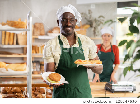 Smiling male baker with pastry in bakehouse 129247630