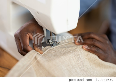 Hands of male seamster sewing fabric on machine Hands of male seamster sewing fabric on machine 129247639
