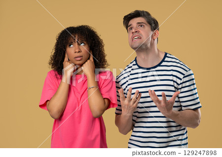 Grumpy man scolds on african american woman. Irritated girlfriend covered ears Grumpy man scolds on african american woman. Irritated girlfriend covered ears 129247898