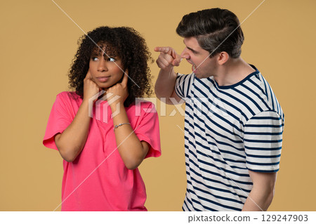 Grumpy man scolds on african american woman. Irritated girlfriend covered ears 129247903