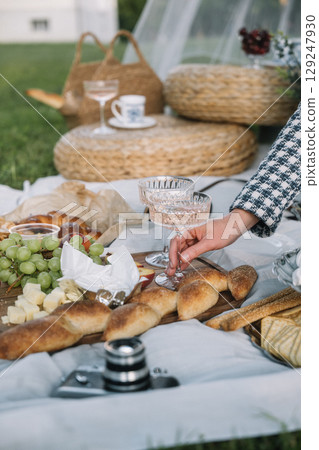 Elegant picnic setup with delicious food and drinks on a sunny day in a grassy area 129247930
