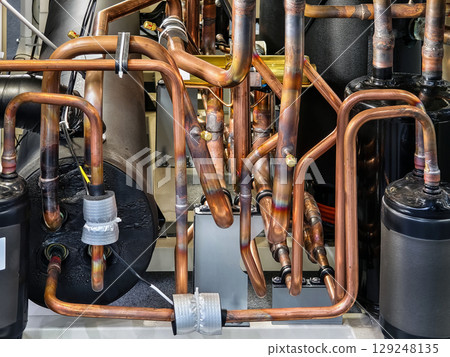 Pipes and tubing in an industrial refrigeration system showcasing intricate design and functionality Pipes and tubing in an industrial refrigeration system showcasing intricate design and functionality 129248135