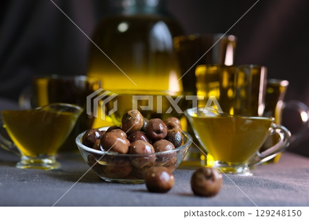 Glass containers with oil and olive twig isolated on white table. Front view. 129248150