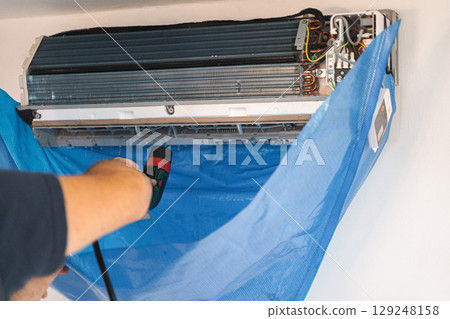 The technician are cleaning the air conditioner by spraying water The technician are cleaning the air conditioner by spraying water 129248158