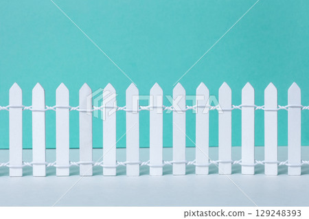 Wooden vintage white picket fence on green background. New painted retro long timber barrier 129248393