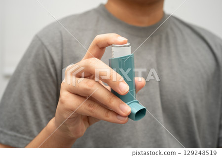 Asthma and chronic obstructive pulmonary disease COPD, Asian young man using metered dose inhaler MDI. Asthma and chronic obstructive pulmonary disease COPD, Asian young man using metered dose inhaler MDI. 129248519