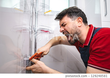 Frustrated plumber screaming while tightening pipe in bathroom Frustrated plumber screaming while tightening pipe in bathroom 129248581