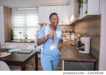 Young nurse drinking coffee in her kitchen before going to work 129248596