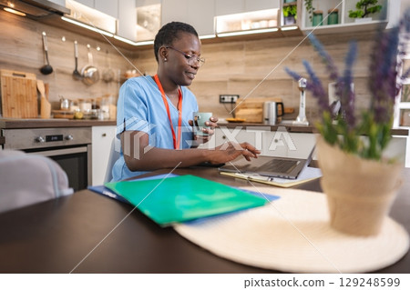 Smiling Nurse Working From Home and Drinking a Coffee 129248599