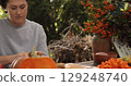 Woman prepares delicious Thanksgiving dishes outdoors with fresh produce and autumn decor, showcasing a cozy atmosphere filled with family spirit and holiday cheer 129248740