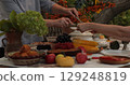 Thanksgiving dinner table filled with delicious food and joyful interactions between family members celebrating a warm autumn gathering outdoors amidst colorful decorations 129248819