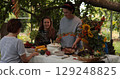 Thanksgiving dinner celebration with family gathering around a beautifully arranged table filled with seasonal food in a cozy garden setting during autumn afternoon 129248825