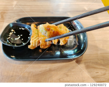 Chopsticks clamping bited fried gyoza. 129248872