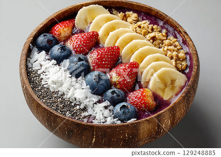 Diet dish. Colorful acai bowl with banana slices, coconut flakes and granola on a white background. Healthy and Wellness Breakfast for luxury resorts. Diet dish. Colorful acai bowl with banana slices, coconut flakes and granola on a white background. Healthy and Wellness Breakfast for luxury resorts. 129248885