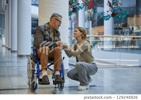 Woman-assistant holding mature mans hands, providing caring and helping 129248926