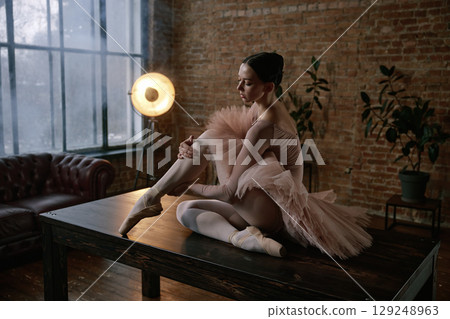 An elegant ballerina is posing gracefully on a table in a beautiful artistic setting 129248963