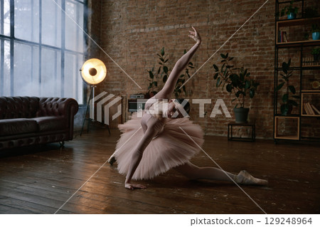 A graceful ballet dancer posing elegantly in a beautiful artistic studio setting 129248964
