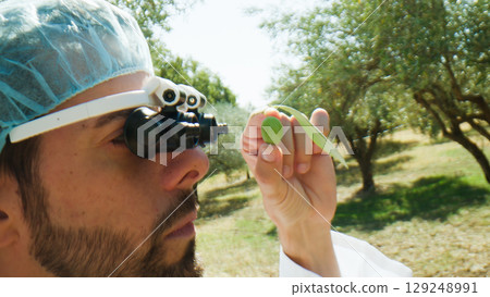 Agronomy scientist looking at an olive with special glasses Agronomy scientist looking at an olive with special glasses 129248991