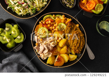 Enjoy a nutritious breakfast with baked sweet potato, carrots, zucchini, chicken breast, and lentil cutlets, complemented by a fresh salad and kiwi for dessert 129249221