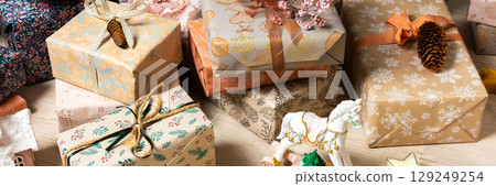 Rustic-themed Christmas gift boxes in natural tones resting beneath a Christmas tree, surrounded by a calm, minimalist holiday atmosphere, banner Rustic-themed Christmas gift boxes in natural tones resting beneath a Christmas tree, surrounded by a calm, minimalist holiday atmosphere, banner 129249254