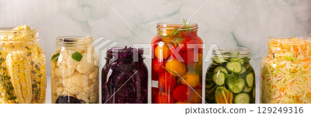 Fresh vegetables like cabbage, tomatoes, cucumbers, corn, peppers and cauliflower, fermenting naturally to boost health and preserve nutrients, banner 129249316