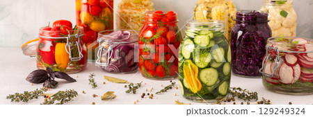 Fresh vegetables like cabbage, tomatoes, cucumbers and radishes, onions, corn, peppers and cauliflower, fermenting naturally to boost health and preserve nutrients, banner 129249324