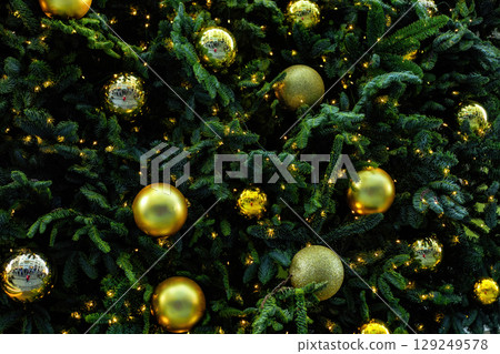 Christmas pattern with green branch pine needles illuminated, golden baubles. Festive fir dark natural ornament 129249578
