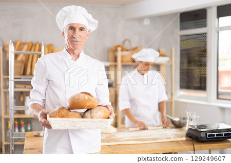 Elderly male seller showing assortment of bakery Elderly male seller showing assortment of bakery 129249607