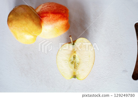 Sliced bisected raw Gala apples on white cutting board, top view. Half an red and yellow riped apple 129249780