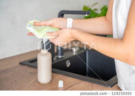 Woman pours soap or detergent from recycled packaging into a reusable bottle. Eco-friendly lifestyle concept Woman pours soap or detergent from recycled packaging into a reusable bottle. Eco-friendly lifestyle concept 129250393