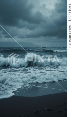 A powerful wave crashing on a dark beach on a stormy day 129251063