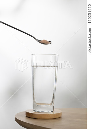 A spoon of Himalayan salt is being added to a glass of drinking water. A spoon of Himalayan salt is being added to a glass of drinking water. 129251430