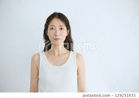 微笑的年輕女子觸摸她的皮膚並進行皮膚護理 — 自然光，白色背景 129251655