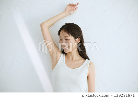 Smiling young woman touching her skin and doing skin care - Natural light, white background Smiling young woman touching her skin and doing skin care - Natural light, white background 129251671
