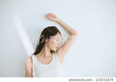 Smiling young woman touching her skin and doing skin care - Natural light, white background 129251674