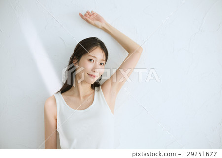 微笑的年輕女子觸摸她的皮膚並進行皮膚護理 — 自然光，白色背景 129251677