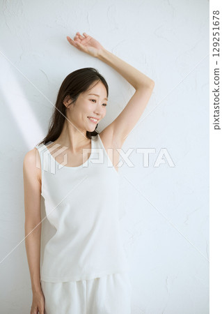 微笑的年輕女子觸摸她的皮膚並進行皮膚護理 — 自然光，白色背景 129251678