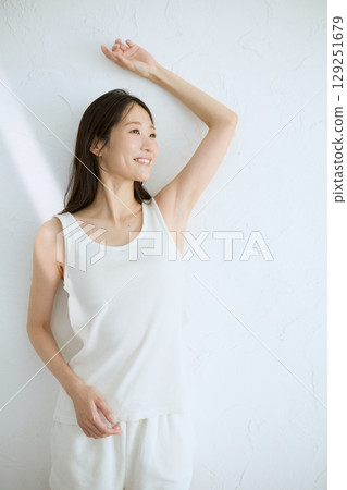 微笑的年輕女子觸摸她的皮膚並進行皮膚護理 — 自然光,白色背景 微笑的年輕女子觸摸她的皮膚並進行皮膚護理 — 自然光,白色背景 129251679