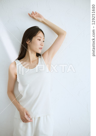 微笑的年輕女子觸摸她的皮膚並進行皮膚護理 — 自然光,白色背景 微笑的年輕女子觸摸她的皮膚並進行皮膚護理 — 自然光,白色背景 129251680