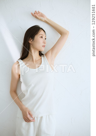 Smiling young woman touching her skin and doing skin care - Natural light, white background 129251681