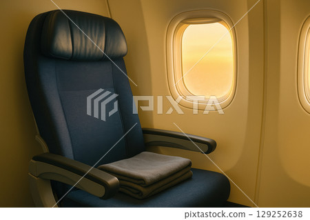 Empty airplane seat by window with folded blanket during golden hour, modern travel comfort interior and peaceful in flight ambiance, AI Generative 129252638