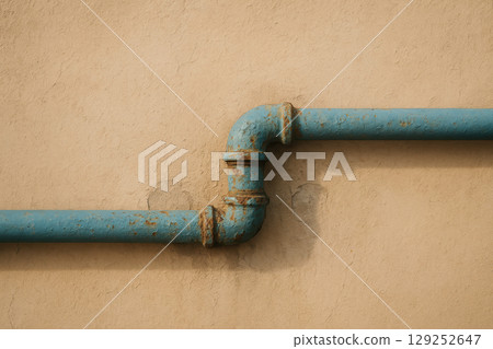 Aged blue metal pipe with rusty fittings runs along beige textured wall, showcasing vintage industrial design and urban detail, AI Generative Aged blue metal pipe with rusty fittings runs along beige textured wall, showcasing vintage industrial design and urban detail, AI Generative 129252647