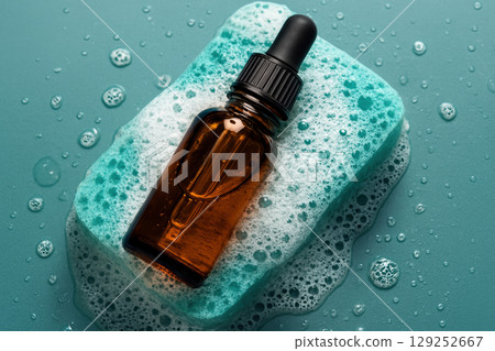 Amber dropper bottle on blue soap with bubbles and water droplets, representing skincare and hygiene concepts, AI Generative 129252667