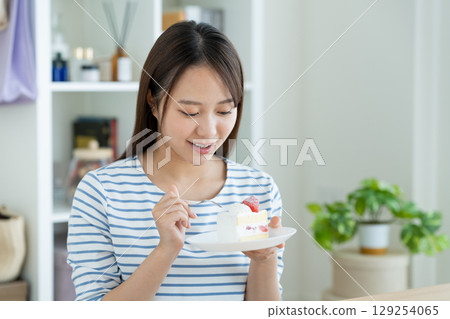 A young woman eating a cake 129254065