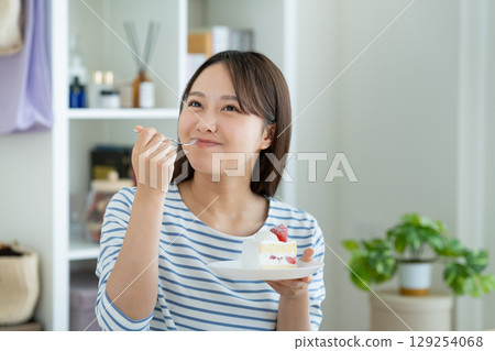 A young woman eating a cake 129254068